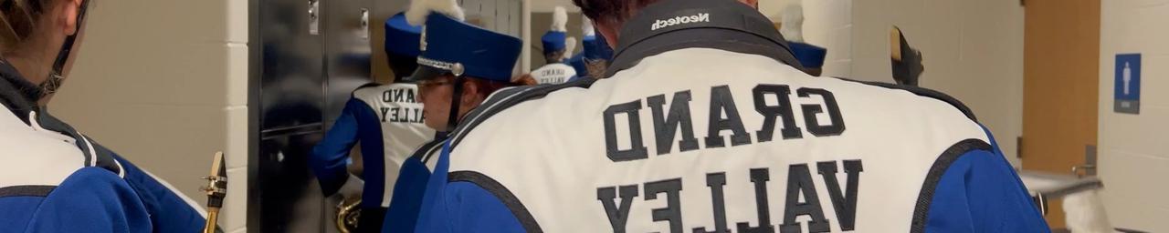 Members of the GVSU Laker Marching Band in uniform walking down a hallway